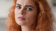 © Yuliia - Close up female face serious angry negative bad mood stressed offended disappointed frustrated portrait ginger hair Caucasian woman girl lady at home looking at camera medicine loan mortgage insurance