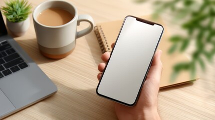 Poster - Person is holding a cell phone with a white screen and a cup of coffee on a table