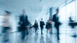 © Harry - Blurred motion captures busy professionals walking swiftly through modern office building hall with large windows casting blue light.