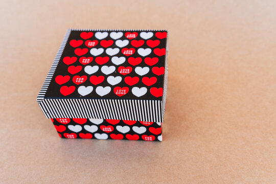 Thank you note that says thank you handwritten with blue pen with a background of a gift box with red and white hearts