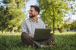 © Miljan Živković - businessman sit on grass in nature and use laptop for work or leisure