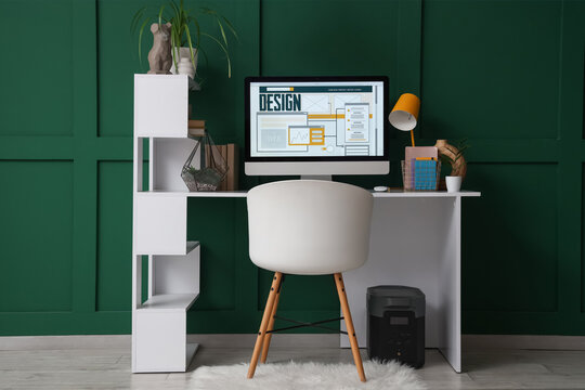 Designer's workplace with computer near green wall in office