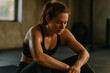 © o.charlyv - Fit woman resting after a workout, sitting in a gym with focused expression