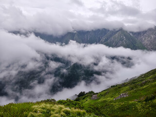 Wall Mural - Misty Mountain Landscape with Dramatic Cloud Cover and Lush Valley View