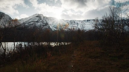 Sun shines over an autumn forest with lake in the Khibiny Mountains, Russia