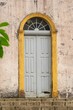 © Wirestock - Single gray paneled door stands beneath a half-moon transom window.