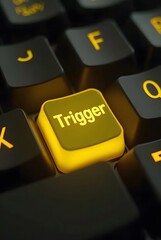 Poster - Illuminated yellow Trigger key on a dark keyboard, vertical composition. A closeup shot emphasizing vibrant color contrast and depth of field.
