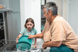 © Victoria - Child helps grandmother to load dishwasher. Family everyday life concept.