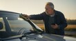 © Creative Concepts  - Senior Man Cleaning Car Windshield at Sunrise for Clear View