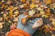 © Anna - Bare feet of a child lying among fallen leaves in a park or forest. Carefree childhood, freedom, rest, walks and enjoying warm autumn days. Active lifestyle, Indian summer.