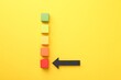 © New Africa - Maximum. Colorful cubes and arrow pointing at red one on yellow background, flat lay