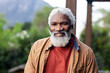 © Wavebreak Media - Senior African American man wearing red shirt tan jacket standing in yard with pergola and mountain