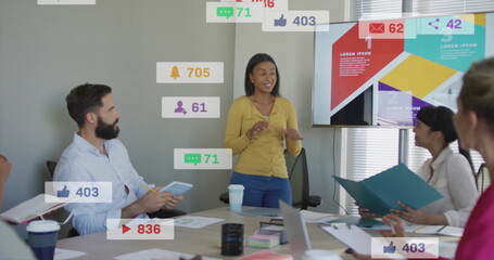 Poster - Woman in mustard cardigan presenting social media metrics on screen in meeting room with laptop