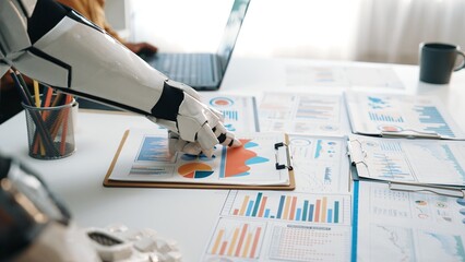 Poster - A robotic hand closely examines business charts and graphs on a clipboard in a modern office. The scene highlights technology's role in data analysis and teamwork.Noogenesis
