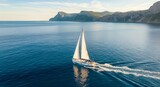 Beautiful white sailboat glides across the calm blue sea, leaving a wake, with majestic coastal cliffs in the background, perfect for summer travel and leisure.