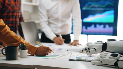 Poster - A diverse team collaborates in a modern office setting, utilizing technology and robot assistance to analyze data, discuss strategies, and plan for future growth.Noogenesis