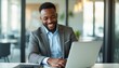 © natakot - Smiling businessman working on a laptop in a modern office