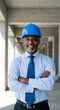 © Mono - Confident African American engineer in a construction site, arms crossed, wearing a blue hard hat and business attire.