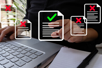 Poster - Close-up of the hands of a person sitting in front of a laptop pointing at an icon of a document with a check mark surrounded by several documents with a cross mark.