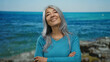 © Krakenimages.com - Grey-haired woman smiling at seaside beach with ocean background, portraying serene joy in outdoor coastal setting for relaxation and wellness imagery.
