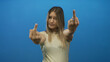 © Krakenimages.com - Woman showing a displeased expression with a cheeky gesture against a bright blue background, highlighting youth and emotion in a bold setting.