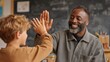 © Abba - Teacher gives high five to student in class, smiling, chalkboard background. Illustrates learning, achievement, motivation, & positive classroom experiences.