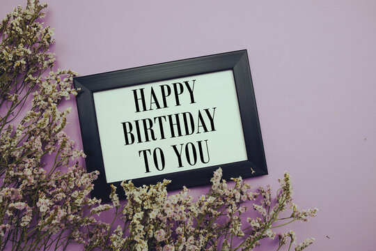 Happy Birthday to you text with flowers bouquet decoration on purple background