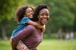 © miss irine - African American mother and young daughter hug, play and have fun together on a summer picnic in a public park. The happy family enjoys quality time outdoors, promoting wellbeing and happiness.
