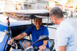 © Mdv Edwards - Middle-aged Southeast Asian tricycle driver in a blue shirt smiling warmly as he engages in cheerful conversation with a customer by the roadside in a sunny local neighborhood.