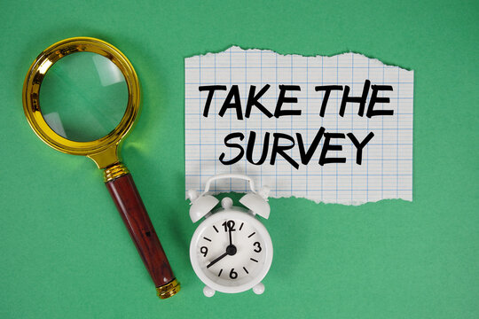Take The Survey text written on paper with magnifying glass and alarm clock