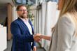 © Moon Safari - Confident businessman in eyeglasses shaking hands with businesswoman while sealing successful agreement in office