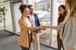 © Moon Safari - Group of business professionals shaking hands and greeting each other in office showing teamwork collaboration