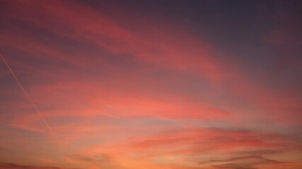 Wall Mural - a radiant sunrise sky timelapse with vibrant orange and pink clouds glowing warmly against a soft bl
