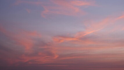 Wall Mural - a vibrant sunset sky timelapse with swirling fiery orange and pink clouds contrasted against a fadin