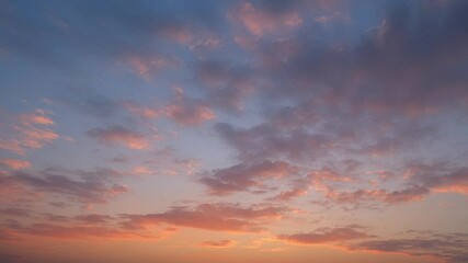 Wall Mural - a mesmerizing sunset sky timelapse with scattered fluffy clouds glowing in warm orange and pink tone