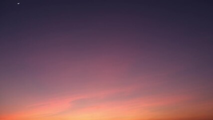 Wall Mural - A serene sunrise sky timelapse showing a gentle gradient from warm golden hues at the horizon to soft purples higher up, with delicate clouds glowing softly in the morning light. Time-lapse.
