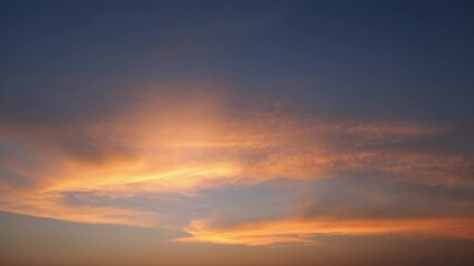Wall Mural - a calming sunset sky timelapse with soft, golden-orange clouds spreading across a deepening blue sky