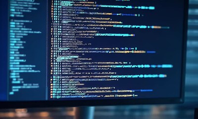 Poster - 
A computer screen displaying lines of code, representing the software development process and coding concept. The background is dark blue with blurred light effects. 