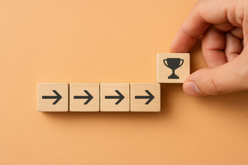 Poster - A concept achievement and steady progress is illustrated by moving an arrow block toward a trophy symbol on a soft orange background