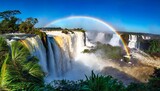 water cascading over the iguacu falls with rainbow in foreground in brazil
