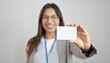 © photostockatinat - Smiling woman holding up a blank business card, perfect for showcasing a professional identity or a simple message.