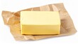 © photostockatinat - A close-up of a block of butter, partially unwrapped and resting on brown paper. The image captures the simplicity and texture of this common food item