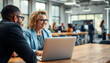 © MdShahajan - Diverse business professionals collaborating and smiling while working on a laptop in a modern office