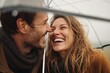 © Vitalii Shkurko - A couple enjoy a moment of spontaneous joy as they laugh together under a large umbrella on a windy day. The love between them shines while surrounded by rain