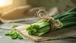 © Bishojit - A bundle of fresh green onions tied with twine rests on a burlap cloth on a wooden surface with scattered slices