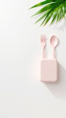 Poster - Minimalist flat lay featuring a blush-toned cutlery set, case, and tropical leaf on a clean, light-colored background for a modern and organic look