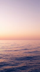 Poster - Soft sunset hues paint the sky above a serene ocean view with gentle ripples across the water's surface