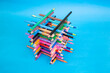 © Dorin - Stacked colored crayons stacked in the shape of a high tower illuminated  on blue background