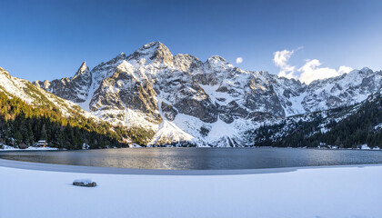 Poster - Snowy mountain lake with clear sky and forest in winter landscape