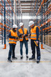 © Koldo_Studio - Warehouse workers and manager wearing safety vests and hardhats are discussing logistics using barcode scanner and tablet in a large distribution center